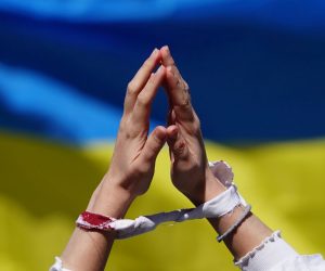 epa09892742 A participant of an Alternativer Ostermarsch (’Alternative Easter March') demonstrates with tied hands and artificial blood in front of a Ukrainian flag under the motto ’Stop Russian Wars’ in Berlin, Germany, 16 April 2022. This year’s peace and Easter marches are taking place under the impression of the ongoing war of Russia on Ukraine. A cooperation, among them Ukrainian, Syrian and Belarusian organizations, called for an alternative Easter march.  EPA/CLEMENS BILAN