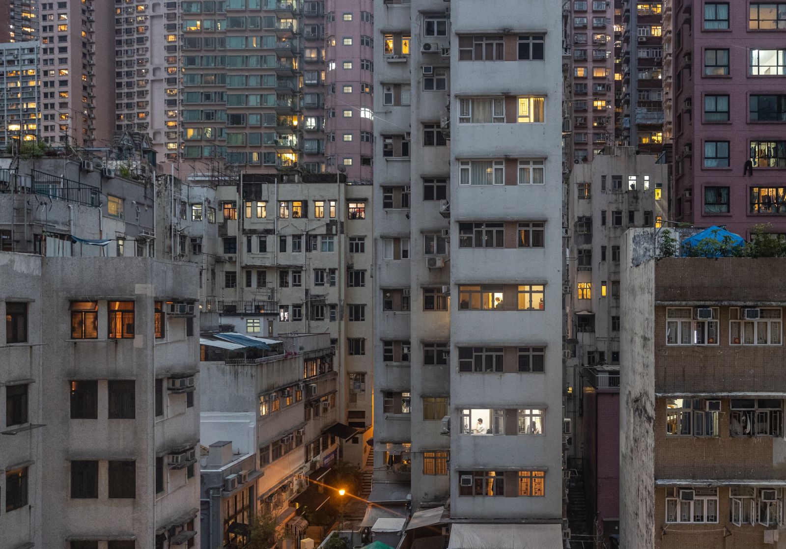 epa09897057 A man, (C), seen through a window, uses his computer at home in Hong Kong, China, 19 April 2022. Hong Kong will ease social distancing measures on April 21, including allowing resumption of dinnertime dine-in services, re-opening of most previously closed premises, as well as updates on the restrictions on gatherings in public and private places.  EPA/JEROME FAVRE