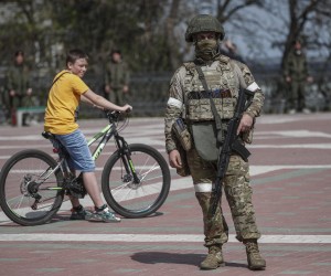 epa09921729 A picture taken during a visit to Mariupol organized by the Russian military shows Russian serviceman on guard during a ceremony of the raising of a replica of the WWII Victory flag in downtown Melitopol, South Ukraine, 01 May 2022. A replica of the WWII Victory flag was raised as a part of celebration for Victory day which is celebrated on 09 May. Located in the south of the Zaporozhye region of Ukraine, the city of Melitopol has been under the control of units of the Russian army and the DPR since the first day of what the Russian president declared a 'special military operation'.  EPA/SERGEI ILNITSKY