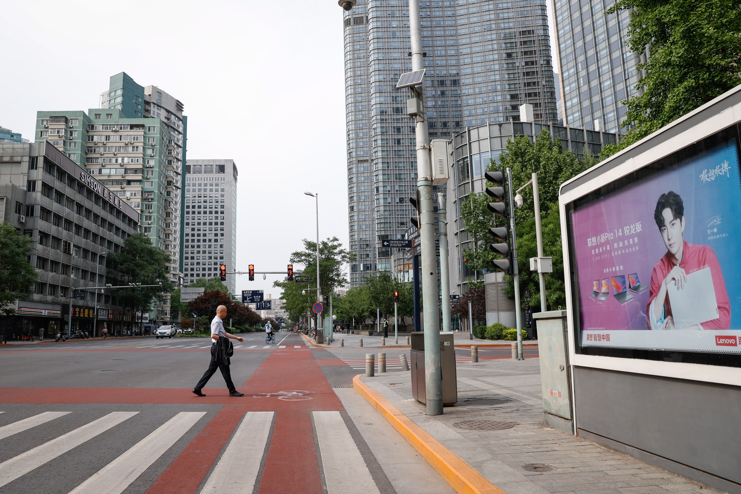 epa09927709 A man crosses a road in the central business district of Beijing, China, 05 May 2022. Beijing urged its residents to work from home following the May Day holiday in an attempt to curb the spread of COVID-19. Dozens of subway stations and bus routes in Beijing shut down and most food establishments with their dine-in services were banned.  EPA/MARK R. CRISTINO