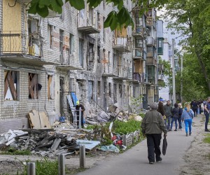 epa09974733 Locals walk past a residential building that was damaged during shelling in the outskirts of Kharkiv, Ukraine, 25 May 2022. Ukraine's second-largest city Kharkiv and its surroundings witnessed repeated airstrikes from Russian forces. On 24 February, Russian troops invaded Ukrainian territory starting a conflict that has provoked destruction and a humanitarian crisis. According to the UNHCR, more than 6.5 million refugees have fled Ukraine, and a further 7.7 million people have been displaced internally within Ukraine since.  EPA/SERGEY KOZLOV