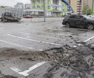 epa09978121 A man walks past a shelling hole and destroyed cars after new shelling in Kharkiv, Ukraine, 26 May 2022. At least seven people were killed and seventeen injured including a child following new shelling in Kharkiv, as city officials stated. Kharkiv, Ukraine's second-largest city, and surrounding areas had been the target of shelling and airstrikes from Russian forces in the past weeks. Russian troops had entered Ukraine on 24 February causing fighting and destruction and a humanitarian crisis.  EPA/SERGEY KOZLOV