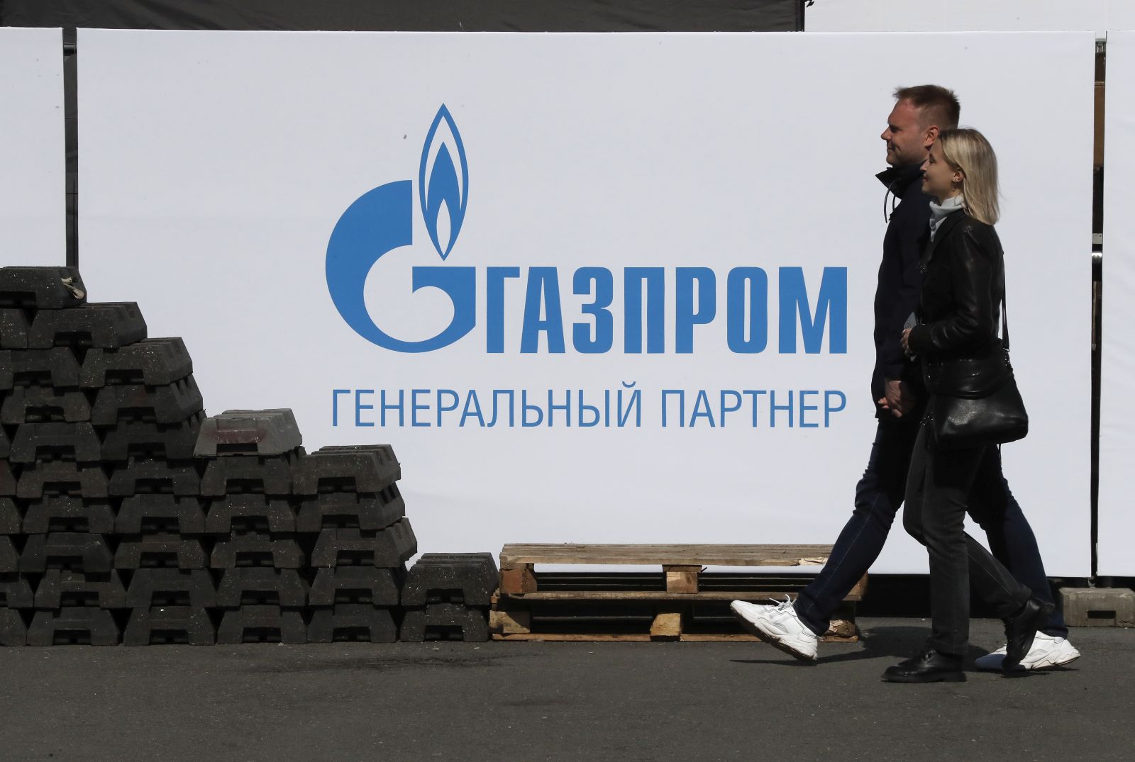 epa09980733 People walk in front of a banner with the Gazprom logo at the Dvortsovaya Square in St. Petersburg, Russia, 27 May 2022.  EPA/ANATOLY MALTSEV