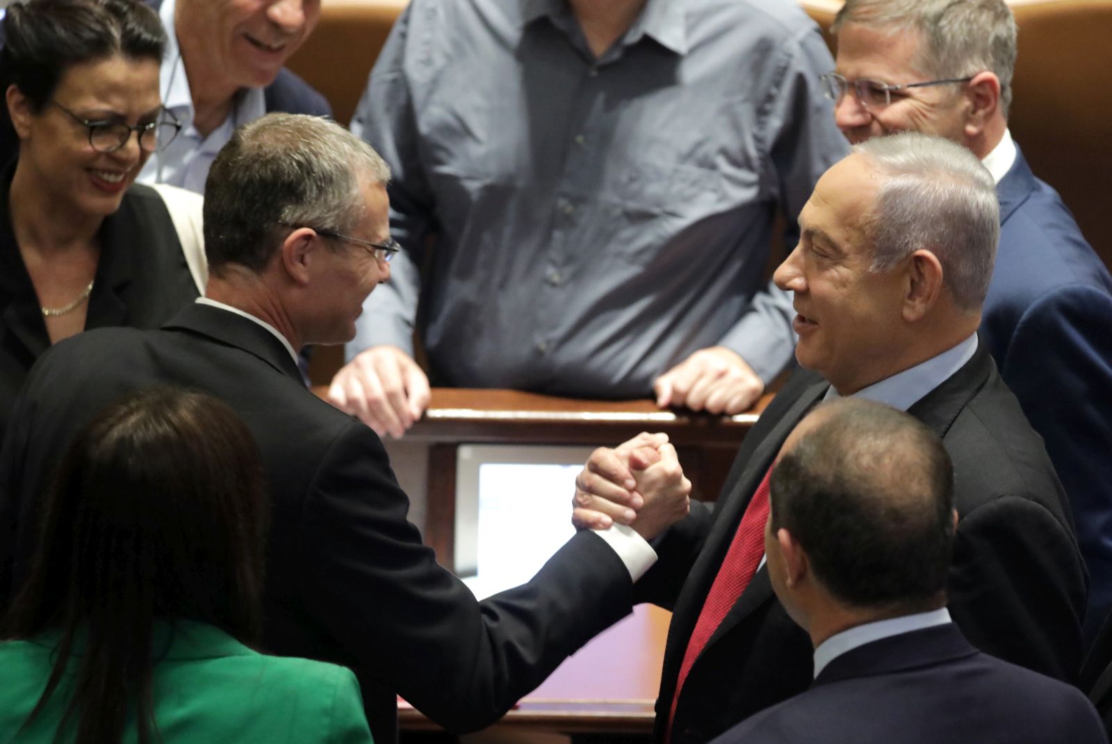 epa10027196 Leader of the opposition and former Israeli Prime Minister Benjamin Netanyahu (R) shakes hands with Yariv Levin (L) during a voting session to dissolve the government in the Knesset Plenum, the Israeli Parliament, in Jerusalem, Israel, 22 June 2022. Parliament members are voting for the law to dissolve the government and go to early elections.  EPA/ABIR SULTAN