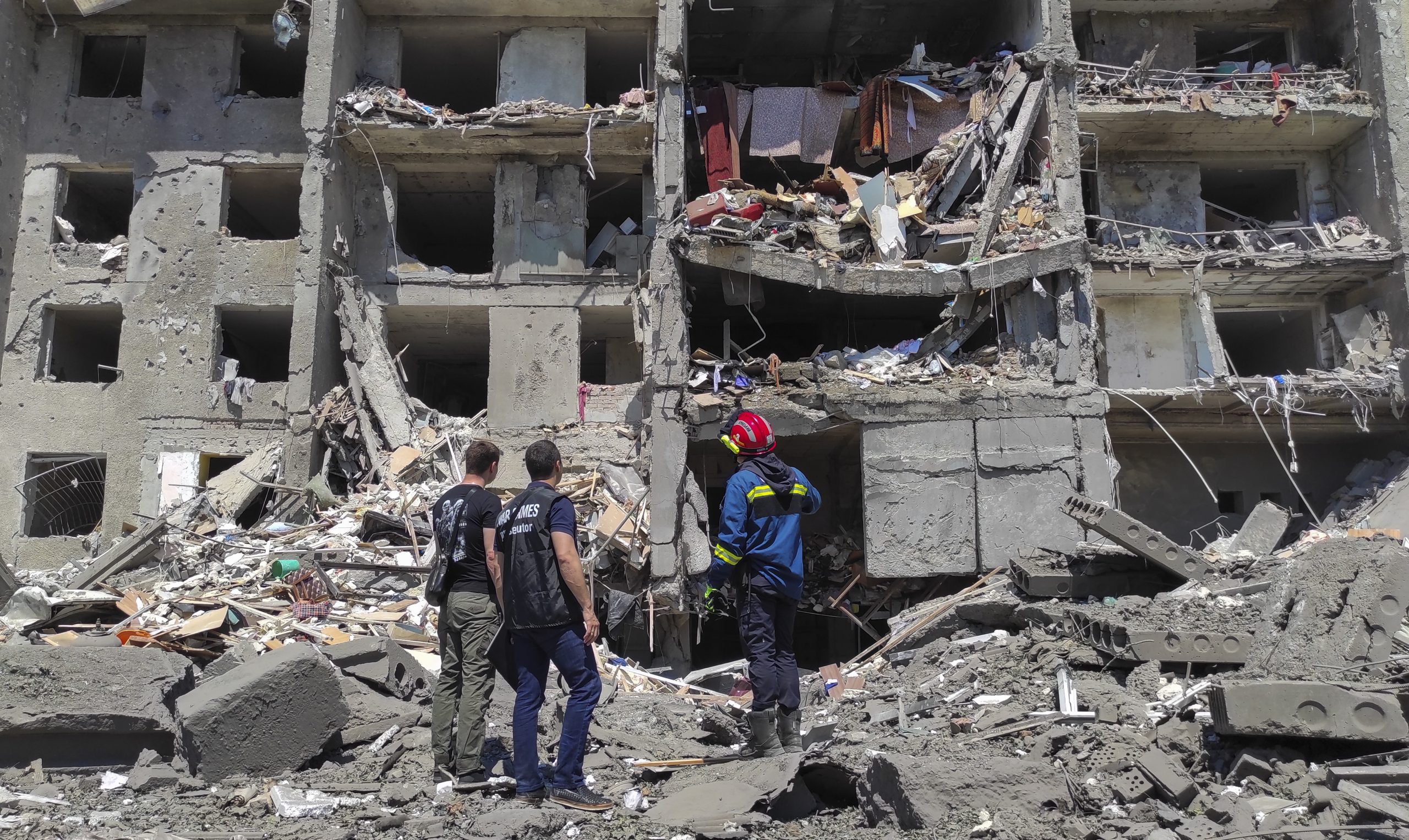 epa10045306 Prosecutor workers and rescuers stand at the scene of a damaged residential building after shelling hit the small town of Serhiivka near Odesa, southern Ukraine, 01 July 2022. At least 19 people were killed and 38 others injured, including six children, after overnight shelling hit a nine-story building and two holiday hotels in Serhiivka, Bilhorod-Dnistrovskyi district, Odesa region, the state emergency service said in a statement on 01 July.  EPA/STRINGER