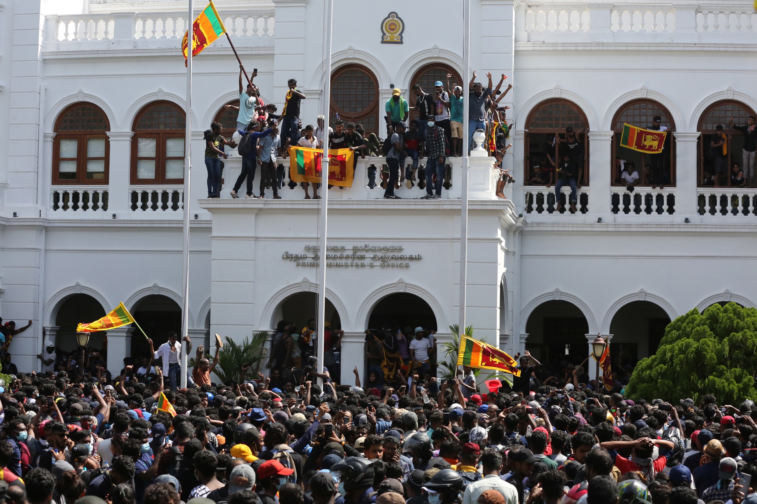 epa10068253 Protesters celebrate after they stormed the Prime Minister's office in Colombo, Sri Lanka, 13 July 2022. Thousands of protesters broke through police barricades and stormed into the Prime Minister's office on 13 July. Sri Lankan authorities declared a state of emergency and imposed a curfew in the Western Province of the country. According to the speaker of parliament, Sri Lankan President Gotabaya Rajapaksa has authorised the prime minister Prime Minister Ranil Wickremesinghe to carry out presidential duties after the president fled to the Maldives after months of protests against the economic crisis.  EPA/CHAMILA KARUNARATHNE