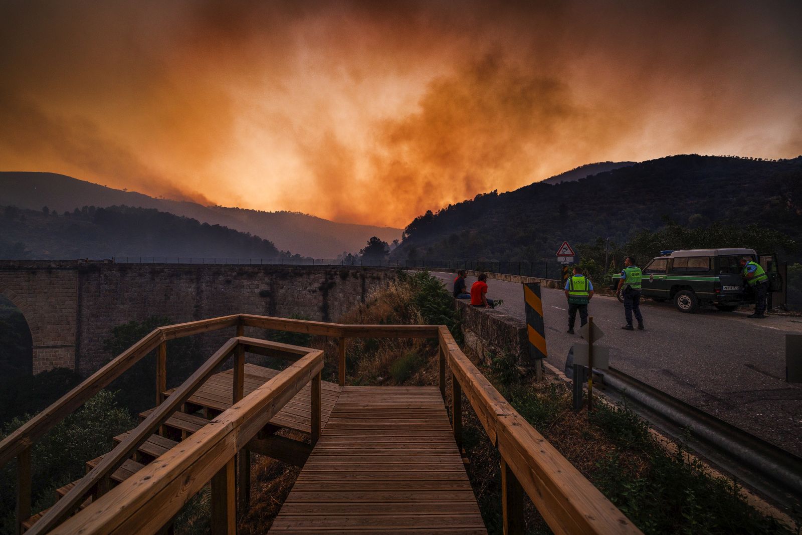 epa10080674 GNR (National Republican Guard) officers and people look in the direction of a forest fire in Cabanas, Valpacos, Portugal, 19 July 2022. 788 operational and 272 vehicles are fighting the forest fire.  EPA/MIGUEL PEREIRA DA SILVA