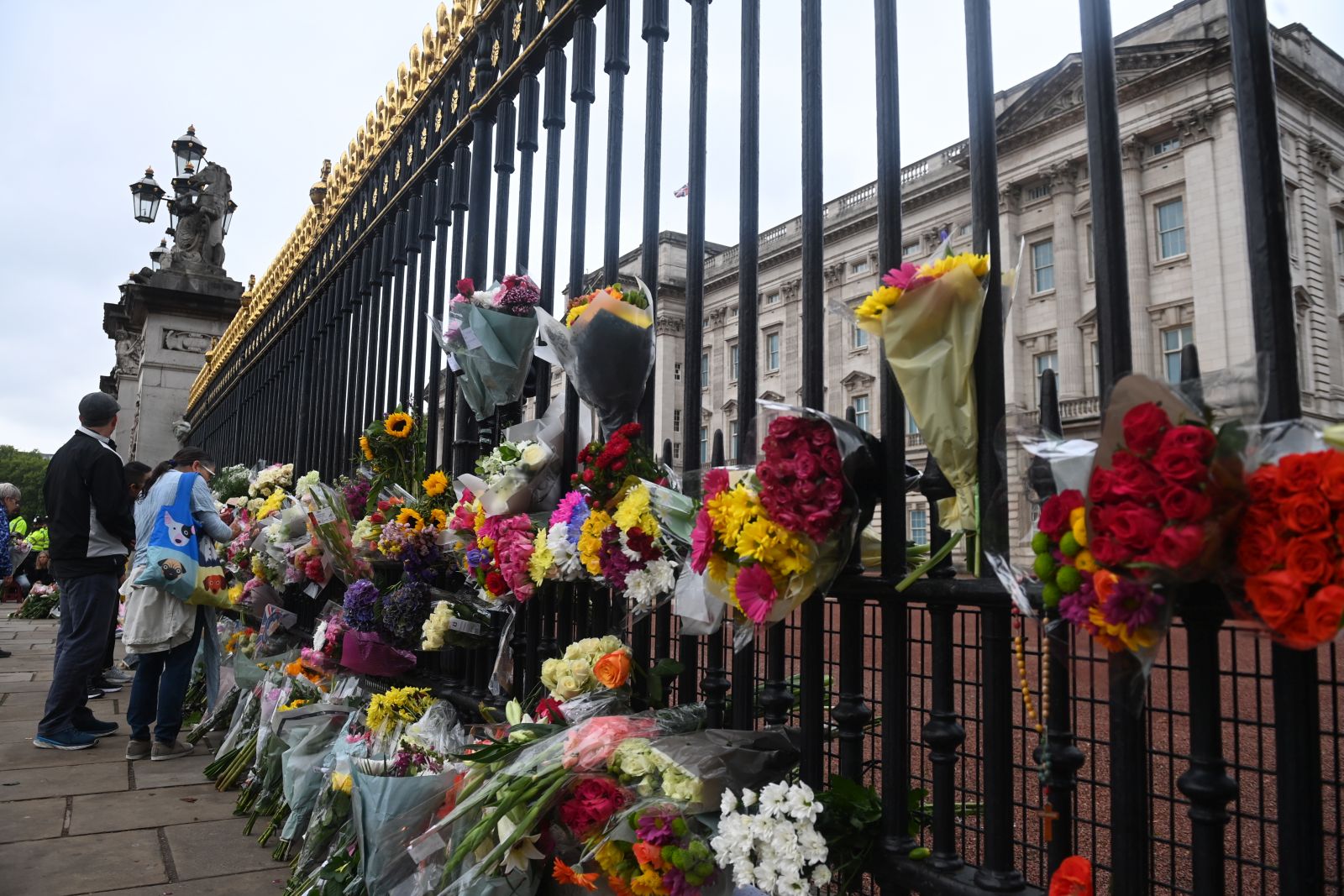 epa10172521 Floral tributes hang from the railings of Buckingham Palace a day after the passing of Queen Elizabeth II, in London, Britain, 09 September 2022. Britain's Queen Elizabeth II died at her Scottish estate on 08 September 2022. The 96-year-old queen was the longest-reigning monarch in British history.  EPA/NEIL HALL