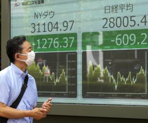 epa10182848 A pedestrian looks at a display showing declines in the Dow Jones Industrial Average (L) and the Nikkei Stock Average (R) during the morning trading session, in Tokyo, Japan, 14 September 2022. The Dow Jones Industrial Average in the US plunged over 1,200 points on 13 September. The Tokyo stock benchmark fell more than 800 points in the morning trading session on 14 September.  EPA/KIMIMASA MAYAMA