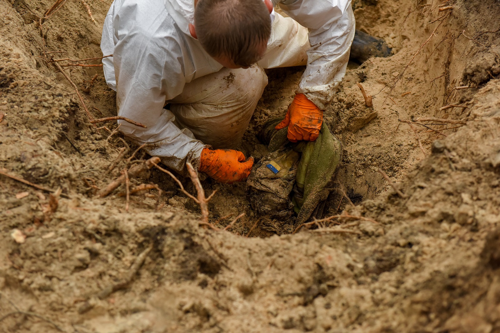 epa10188573 A forensic technician inspects inspects a body in a grave near Izyum, Kharkiv region, northeastern Ukraine, 16 September 2022. A mass burial site was found after Ukrainian troops recaptured the town of Izyum. According to the head of the investigative department of the police of the Kharkiv region, the burial site, one of the largest in a recaptured city so far, counts more than 440 separate graves. The Ukrainian army pushed Russian troops from occupied territory in the northeast of the country in a counterattack. Kharkiv and surrounding areas have been the target of heavy shelling since February 2022, when Russian troops entered Ukraine starting a conflict that has provoked destruction and a humanitarian crisis.  EPA/OLEG PETRASYUK -- ATTENTION EDITORS: GRAPHIC CONTENT