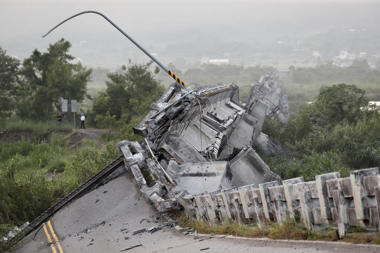 epa10192681 A Taiwanese resident walks past the Gaoliao bridge that collapsed after a magnitude 6.8 earthquake hit Yuli Township; in Hualien County, Taiwan, 19 September 2022. The series of earthquakes and aftershocks on 18 September, caused minor structural damage and derailed a train in eastern Taiwan.  EPA/RITCHIE B. TONGO