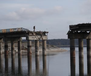 epa10221538 A Ukrainian soldier on the damaged bridge over the Siverskyi Donets river in Staryi Saltiv, the newly liberated city east of Kharkiv, Ukraine, 29 September 2022. The Ministry of Infrastructure of Ukraine reports that over 350 bridges and 49 railway bridges have been damaged, while thousands of kilometers of highways were completely destroyed in Ukraine so far during the on-going war.  EPA/ATEF SAFADI