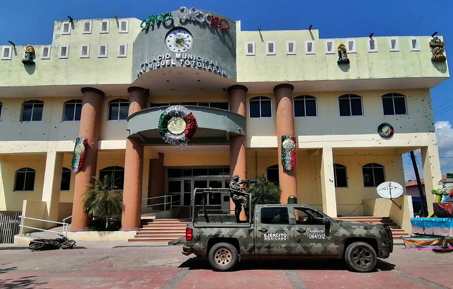 epa10226078 Members of the Mexican Army guard the area where an armed attack took place, at the Municipal Palace of San Miguel Totolapan, Guerrero, Mexico, 05 October 2022. An armed group assassinated the mayor of San Miguel Totolapan, Conrado Mendoza Almeda, a municipality located in the Tierra Caliente region in the state of Guerrero, southern Mexico, in an attack in which at least 10 people are said to have been killed.  EPA/Stringer