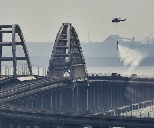 epa10230634 A firefighter helicopter pours water on fire on a collapsed part of the Kerch Strait bridge in Crimea, 08 October 2022. According to Russian authorities, "an explosion was set off at a cargo vehicle on the motorway part of the Crimean bridge on the side of the Taman peninsula, which set fire to seven fuel tanks of a train that was en route to the Crimean peninsula. Two motorway sections of the bridge partially collapsed."  EPA/STRINGER