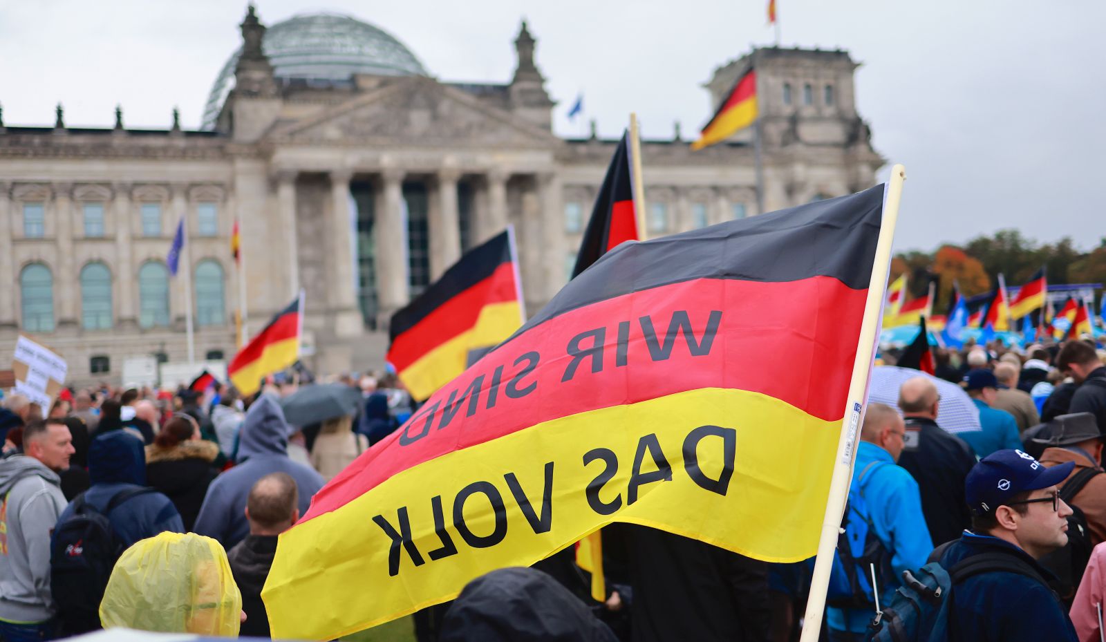 epa10230595 A German national flag with 'We are the people' inscription as protesters demonstrate in front of Reichstags building in Berlin, Germany, 08 October 2022. The right-wing populist Alternative for Germany (Alternative fuer Deutschland, AfD) party called for a demonstration against rising prices.  EPA/HANNIBAL HANSCHKE