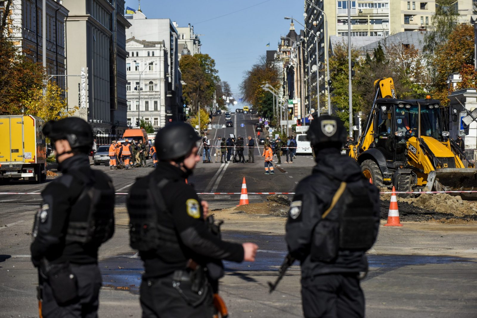 epaselect epa10234457 Armed police officers guard the area as municipal service workers (back) conduct repair works on a road after shelling in downtown Kyiv (Kiev), Ukraine, 10 October 2022. Explosions have been reported in several districts of the Ukrainian capital Kyiv on 10 October. At least 11 people died and dozens injured as a result of rocket attacks, the State Emergency Service (SES) of Ukraine said. Russian troops entered Ukraine on 24 February 2022 starting a conflict that has provoked destruction and a humanitarian crisis.  EPA/OLEG PETRASYUK