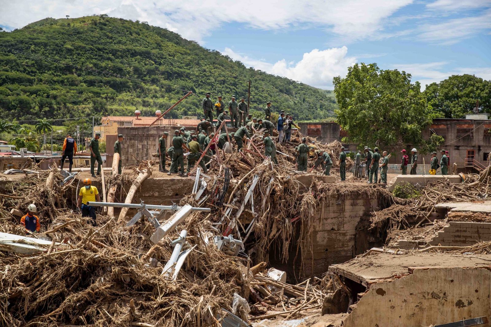epa10235378 Officials survey the damage caused by the overflow of the Los Patos stream, in Las Tejerias, Aragua state, Venezuela, 10 October 2022. At least 36 people lost their lives due to the landslide on Saturday in the town of Tejerías, in central Venezuela, while another 56 citizens are still missing, according to the information offered by the Minister of the Interior and Justice, Remigio Ceballos.  EPA/Miguel Gutierrez