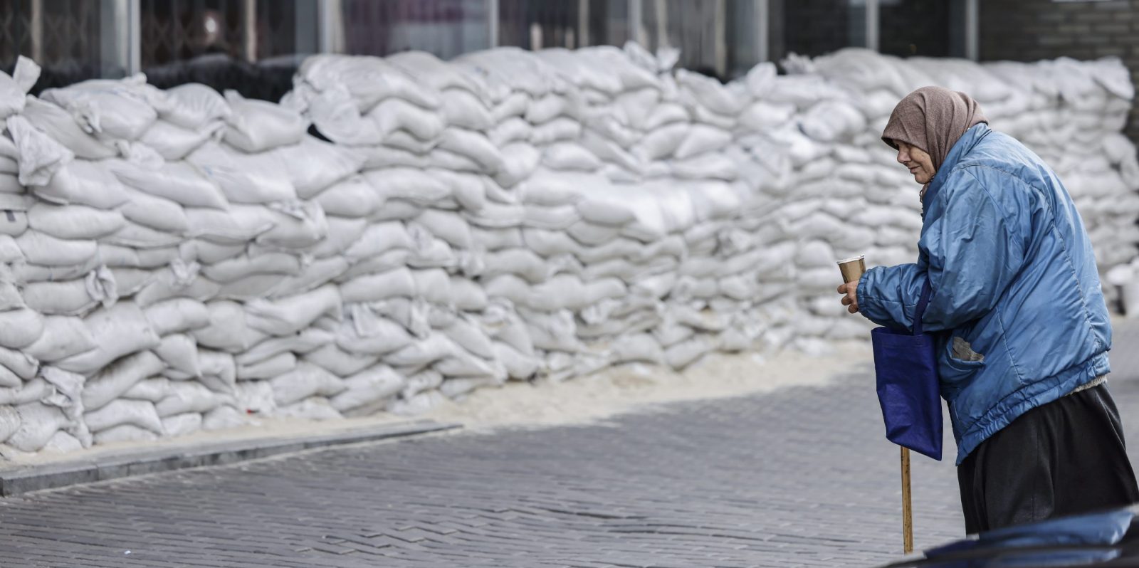 epa10268571 A woman begs for money in front of a barricade of sandbags in Dnipro, Ukraine, 27 October 2022. Russian troops on 24 February entered Ukrainian territory, starting a conflict that has provoked destruction and a humanitarian crisis.  EPA/HANNIBAL HANSCHKE