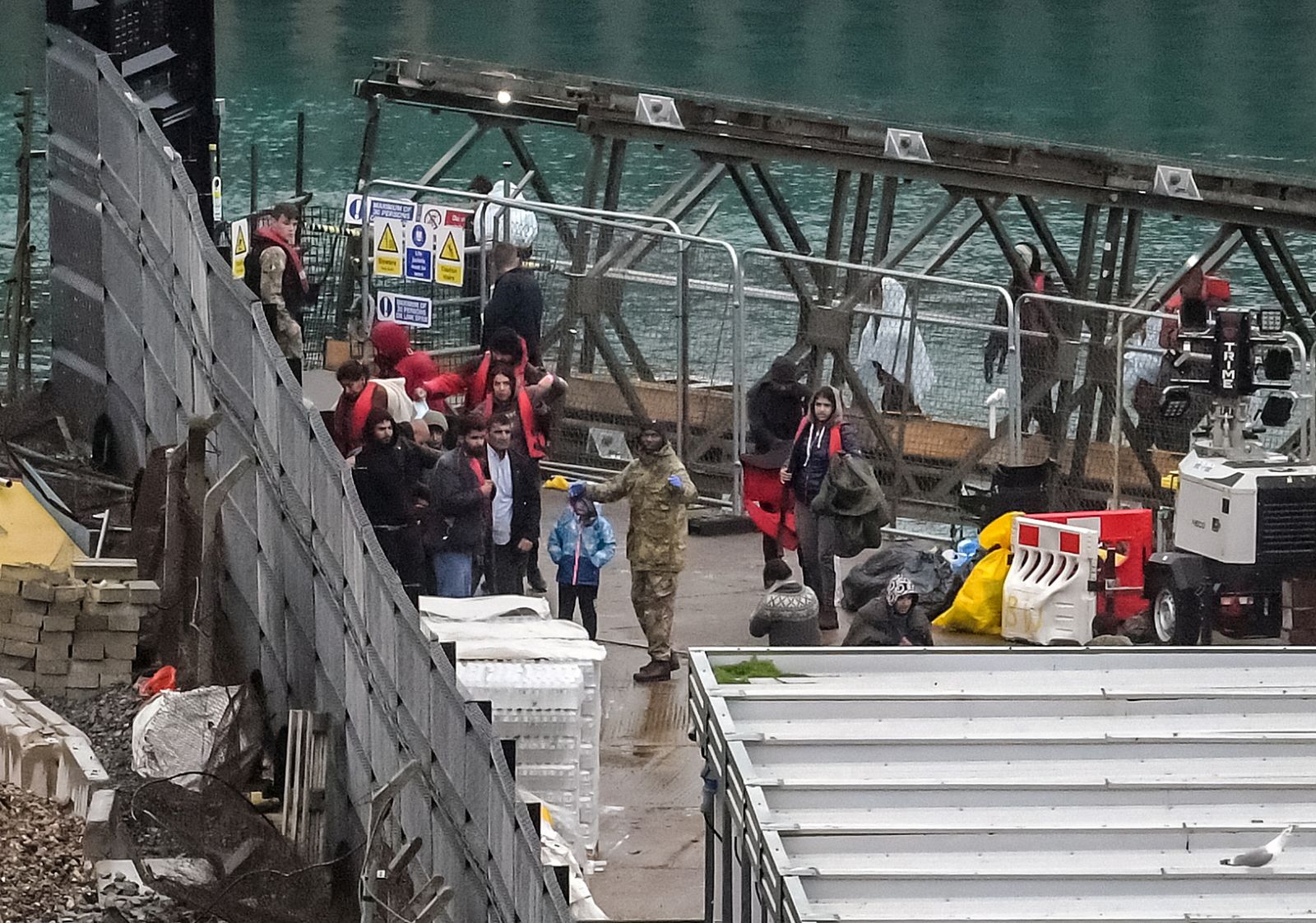 epa10275014 People arriving at a migrant processing centre shortly before a suspected attack in Dover, Britain, 30 October 2022. A suspected attacker was believed to have thrown petrol bombs at the migrant centre before taking his own life, according to witnesses.  EPA/STUART BROCK