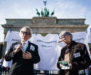 epa10260736 Activists of Amnesty International embodying representatives of FIFA (Federation Internationale de Football Association) and the state of Qatar pose in front of symbolically cleanly washed white t-shirts on a rope, in front of the Brandenburg Gate in Berlin, Germany, 23 October 2022. Amnesty International demonstrated with a role play against sportswashing and criticised the human rights situation in Qatar prior to the FIFA World Cup Qatar 2022.  EPA/CLEMENS BILAN