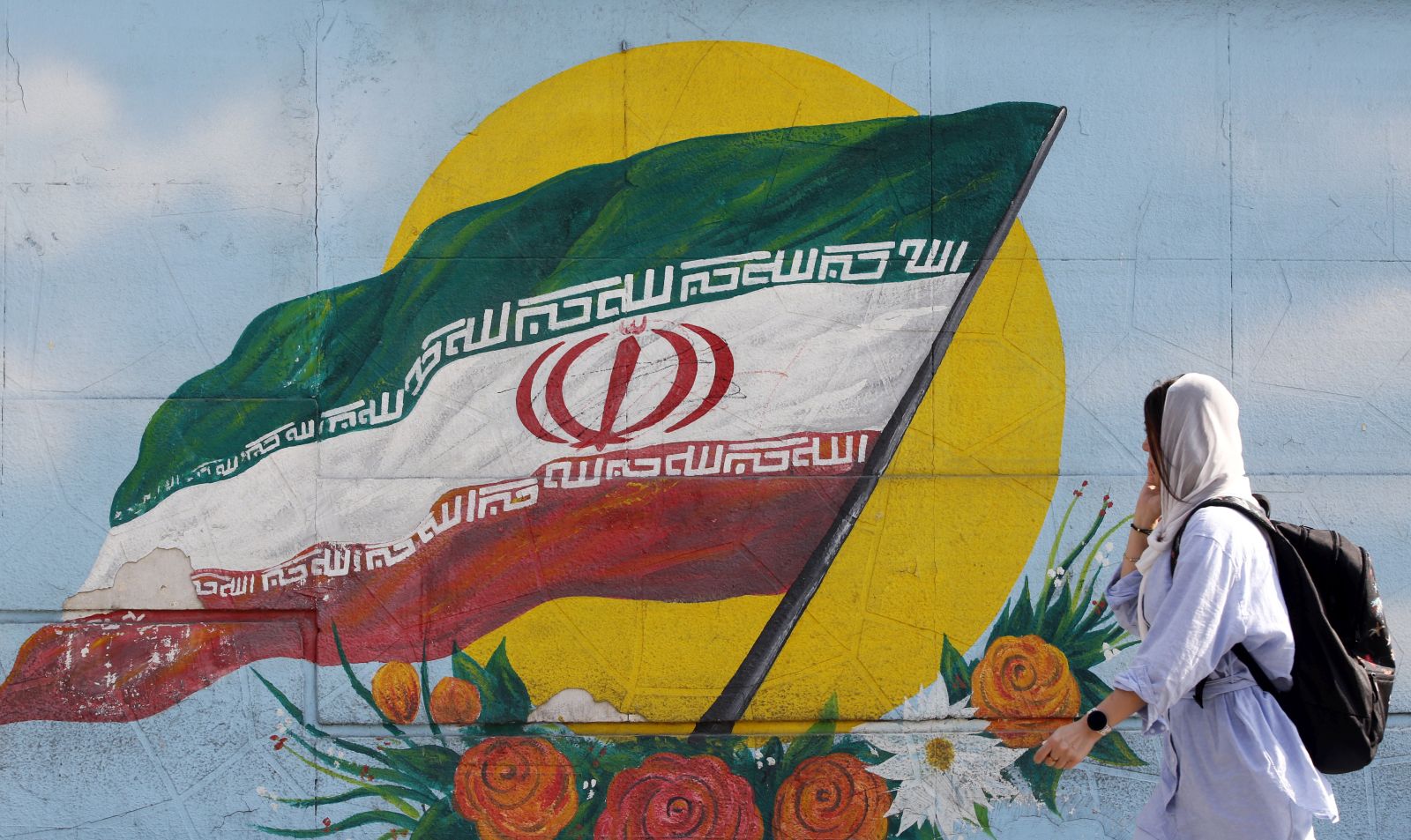 epa10295546 A woman walks past a graffiti showing the Iranian national flag in Tehran, Iran, 09 November 2022. Iran has been rocked by anti-government protests, with supporters worldwide, following the death in September 2022 of Masha Amini, a 22-year-old girl who died while in police custody after being detained for breaking Iran's strict dress code for women. Iranian leaders condemned the protests and accused the United States and Israel of planning the uprising.  EPA/ABEDIN TAHERKENAREH