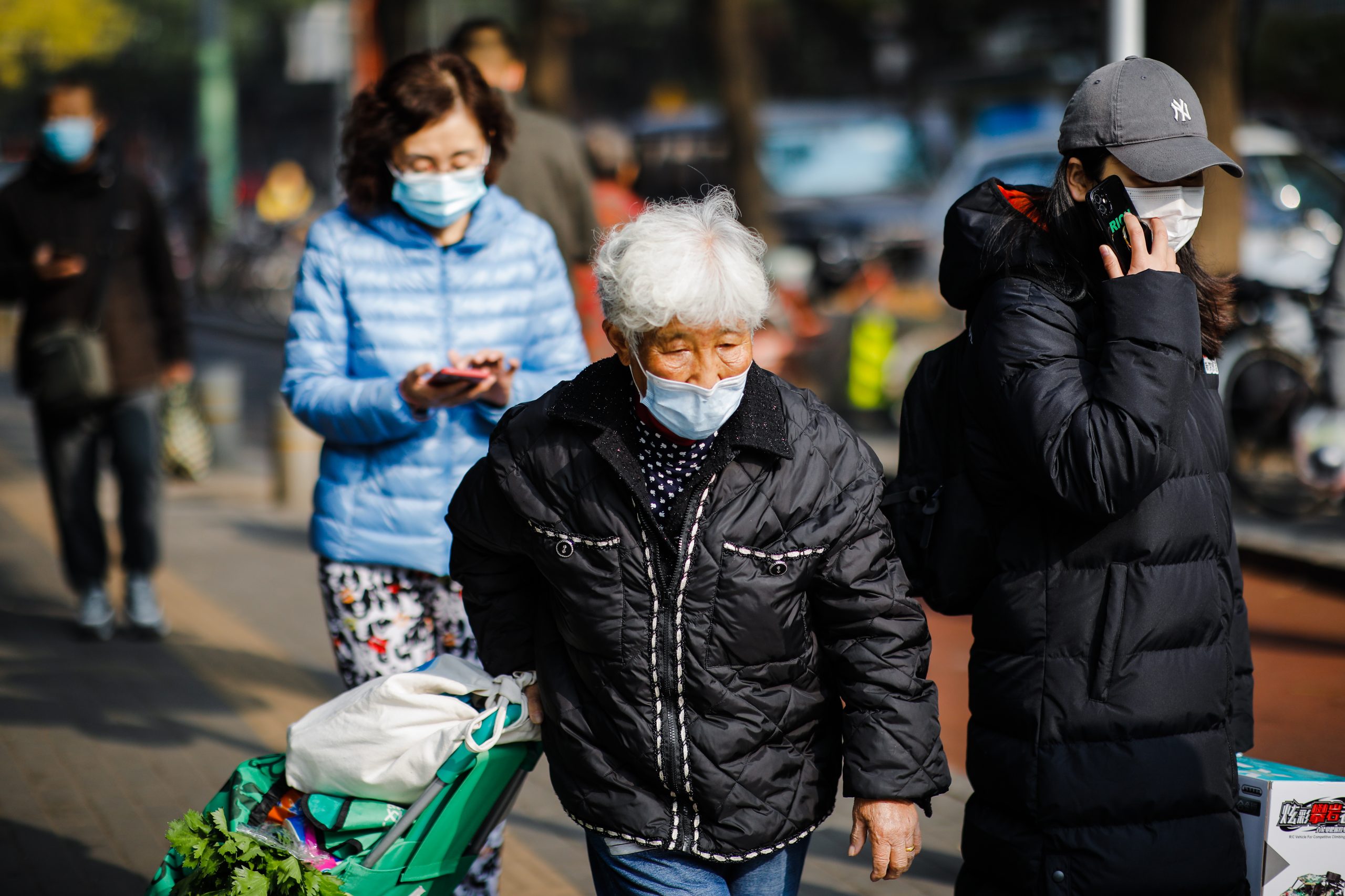 epa10297501 An elderly woman wearing a face mask walks on the street with her vegetable basket in Beijing, China, 10 November 2022. According to the National Health Commission report on 09 November, little over 30 new locally transmitted COVID-19 cases were detected in Beijing, the highest recorded in five months. More than 10 compounds in the Chaoyang district were put under lockdown.  EPA/WU HAO