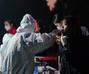 epa10305083 A woman undergoes a swab test to detect COVID-19 at a makeshift testing site in Chaoyang district in Beijing, China, 14 November 2022. According to the National Health Commission report on 14 November, little over 70 new locally transmitted COVID-19 cases were detected in the Chaoyang district in Beijing. The population is currently required to present a negative PCR test result taken within 24 hours in order to enter public venues like restaurants and shopping malls.  EPA/WU HAO