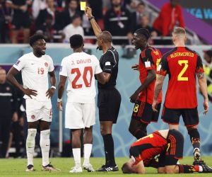 epa10323785 Referee Janny Sikazwe (C) shows the yellow card to Alphonso Davies of Canada (L) during the FIFA World Cup 2022 group F soccer match between Belgium and Canada at Ahmad bin Ali Stadium in Doha, Qatar, 23 November 2022.  EPA/Rungroj Yongrit