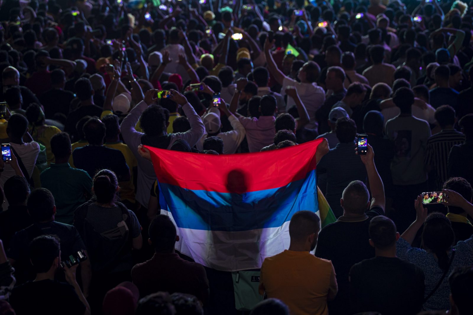epaselect epa10326132 A fan holds the Serbian flag as people watch the FIFA World Cup Qatar 2022 match between Brazil and Serbia at the Fan Festival in the centre of Doha, Qatar, 24 November 2022.  EPA/MARTIN DIVISEK
