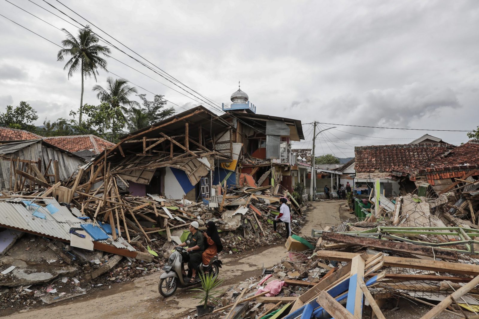 epa10329366 Motorists ride past collapsed houses affected by the 5.6 magnitude earthquake in Cianjur, West Java, Indonesia, 26 November 2022. According to the National Disaster Management Authority (BNPB), at least 310 people killed and 24 missing after 5.6 magnitude earthquake hit southwest of Cianjur, West Java on 21 November 2022.  EPA/MAST IRHAM