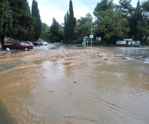 18.11.2022., Malinska - Vodena bujica slijeva se kroz centar Malinske prema moru. Gradjani uklanjaju posljedice poplave koju je izazvala jaka kisa u jutarnjim satima. . Photo: Goran Kovacic/PIXSELL