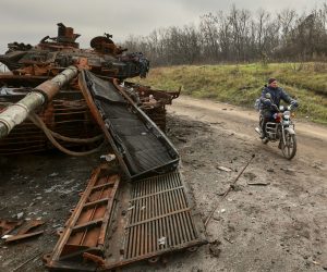 epa10296694 A local man rides a motor bike past a destroyed tank in the Kharkiv region, Ukraine, 09 November 2022. A counter-offensive by Ukrainian forces led to the withdrawal of Russian troops who occupied territory in the northeast of the country. Kharkiv and surrounding areas have been the target of heavy shelling since February 2022, when Russian troops entered Ukraine starting a conflict that has provoked destruction and a humanitarian crisis.  EPA/SERGEY KOZLOV