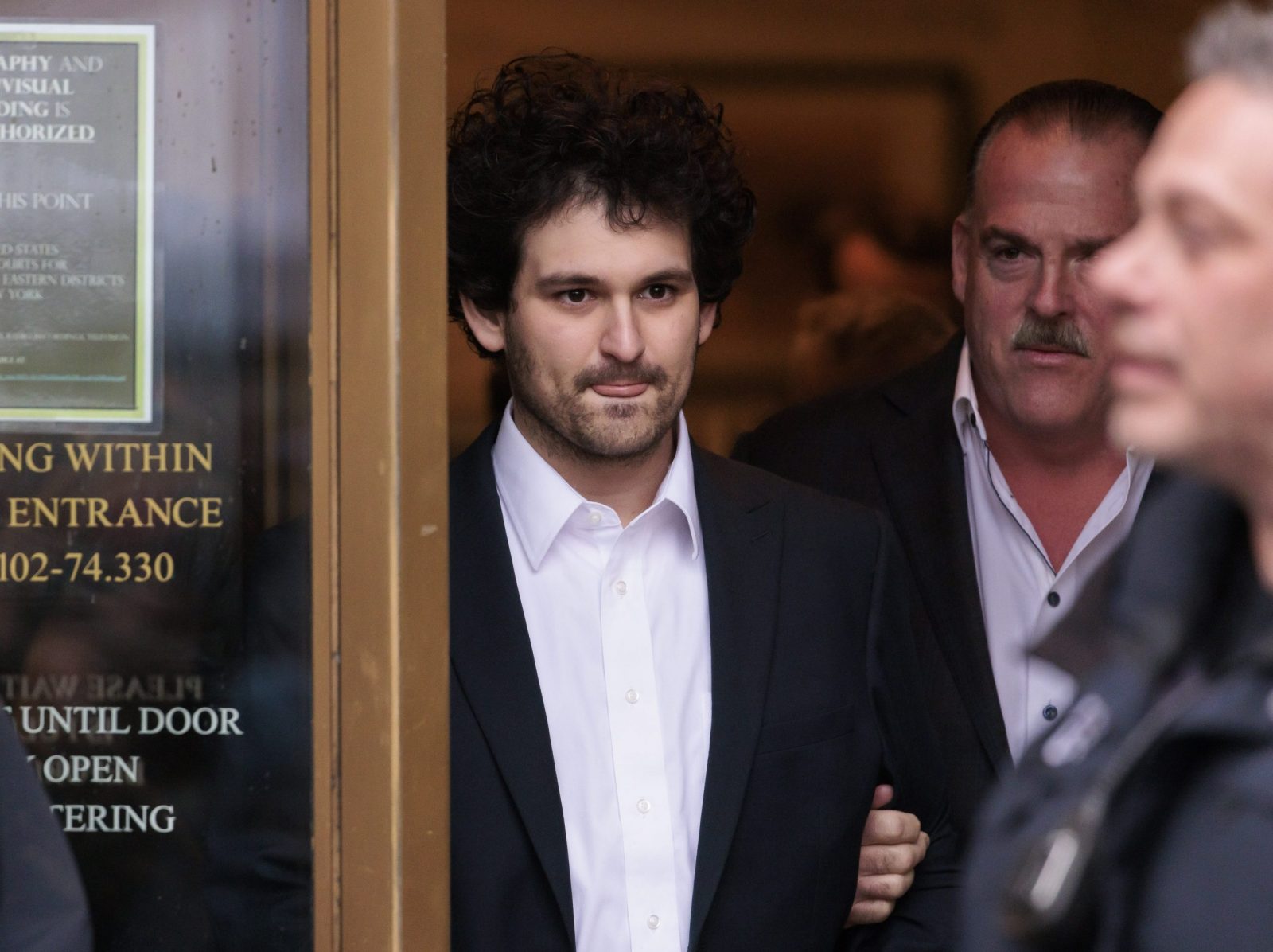 epa10376656 Cryptocurrency entrepreneur Sam Bankman-Fried (C) is lead out of an U.S. Federal Courthouse after being released on bail following an arraignment in New York, New York, USA, 22 December 2022. Bankman-Fried,  who was extradited to the U.S. from the Bahamas yesterday, is facing federal charges that he used money from investors illegally for personal gain.  EPA/JUSTIN LANE