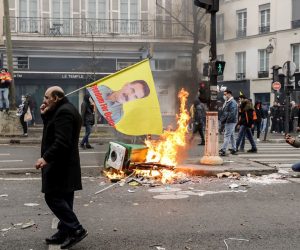 epa10377638 A protestor walks past burning debris following clashes with Police in Paris after demonstrations against a gun attack in the capital, France, 24 December 2022. Three people were killed and others seriously injured after a gunman opened fire outside a Kurdish cultural center in central Paris on 23 December.  EPA/TERESA SUAREZ