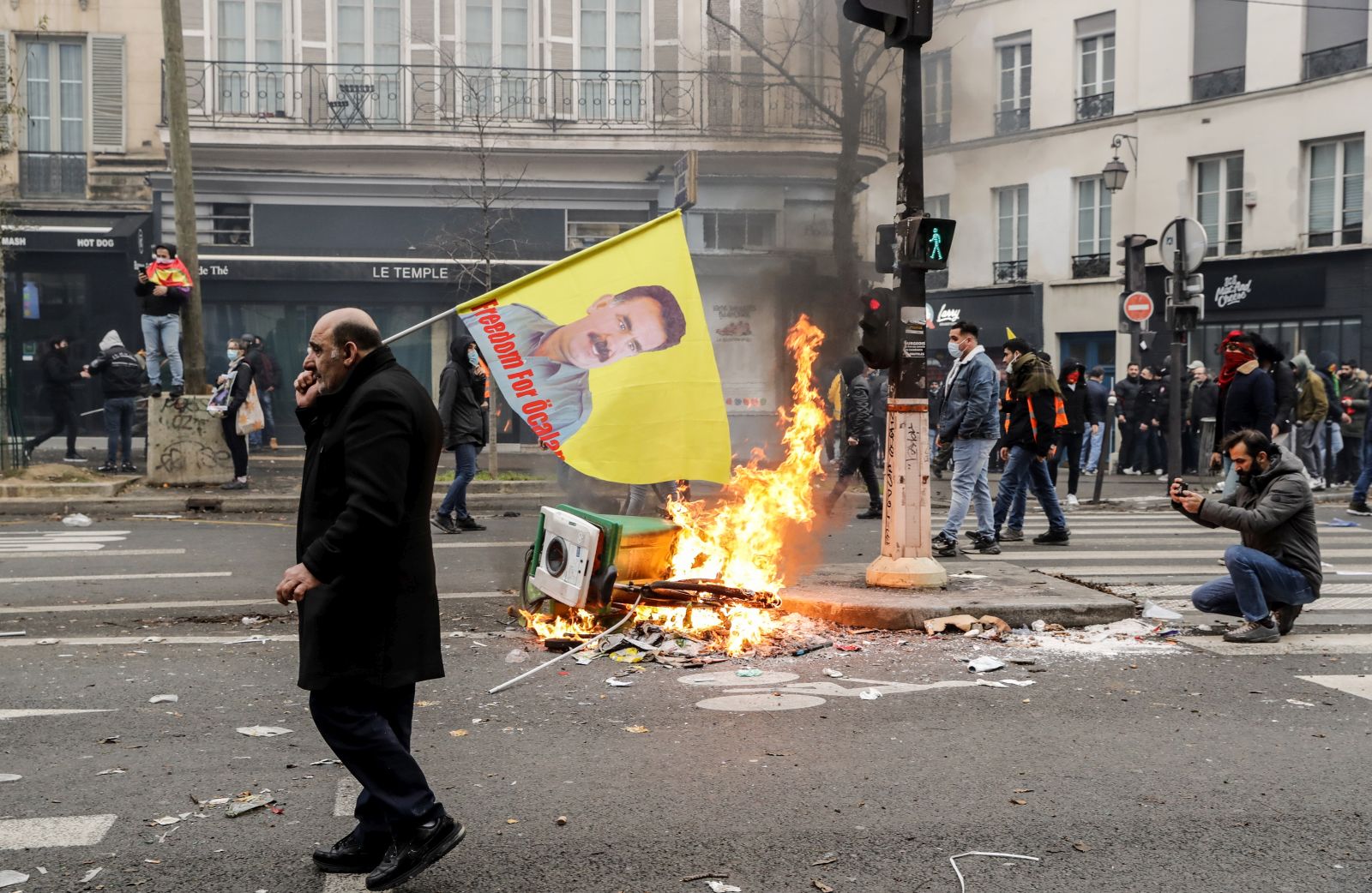epa10377638 A protestor walks past burning debris following clashes with Police in Paris after demonstrations against a gun attack in the capital, France, 24 December 2022. Three people were killed and others seriously injured after a gunman opened fire outside a Kurdish cultural center in central Paris on 23 December.  EPA/TERESA SUAREZ