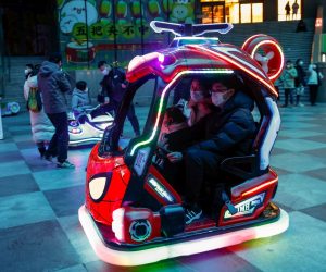 epa10383803 A family rides a Spiderman themed vehicle at a shopping district amid the COVID-19 outbreak during New Year's Eve in Beijing, China, 31 December 2022. The World Health Organization (WHO) has urged Chinese officials to share real-time information on COVID-19 as infections continue to surge after restrictions have been lifted around the country.  EPA/MARK R. CRISTINO