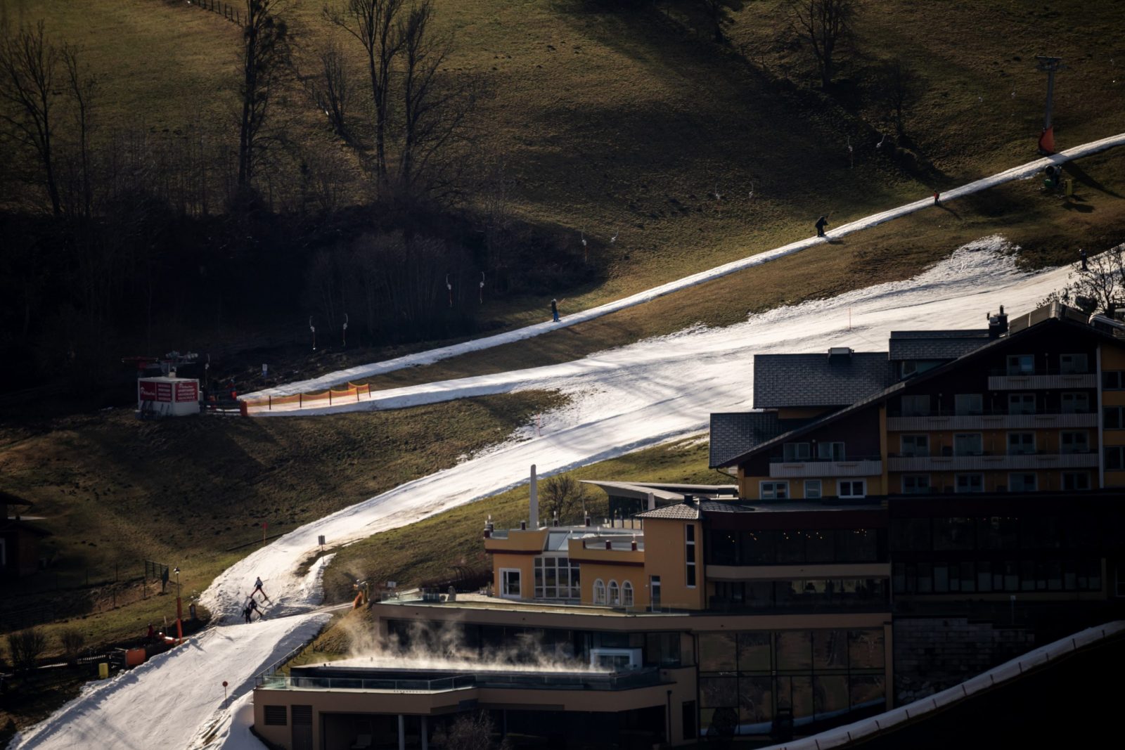 epa10392241 Skiers go downhill a slope in an otherwise snowless surrounding in Schladming, Austria, 06 January 2023. Countries across Europe have been experiencing record-breaking January temperatures, according to meteorologists. At least eight European countries have recorded their warmest January day ever.  EPA/Christian Bruna