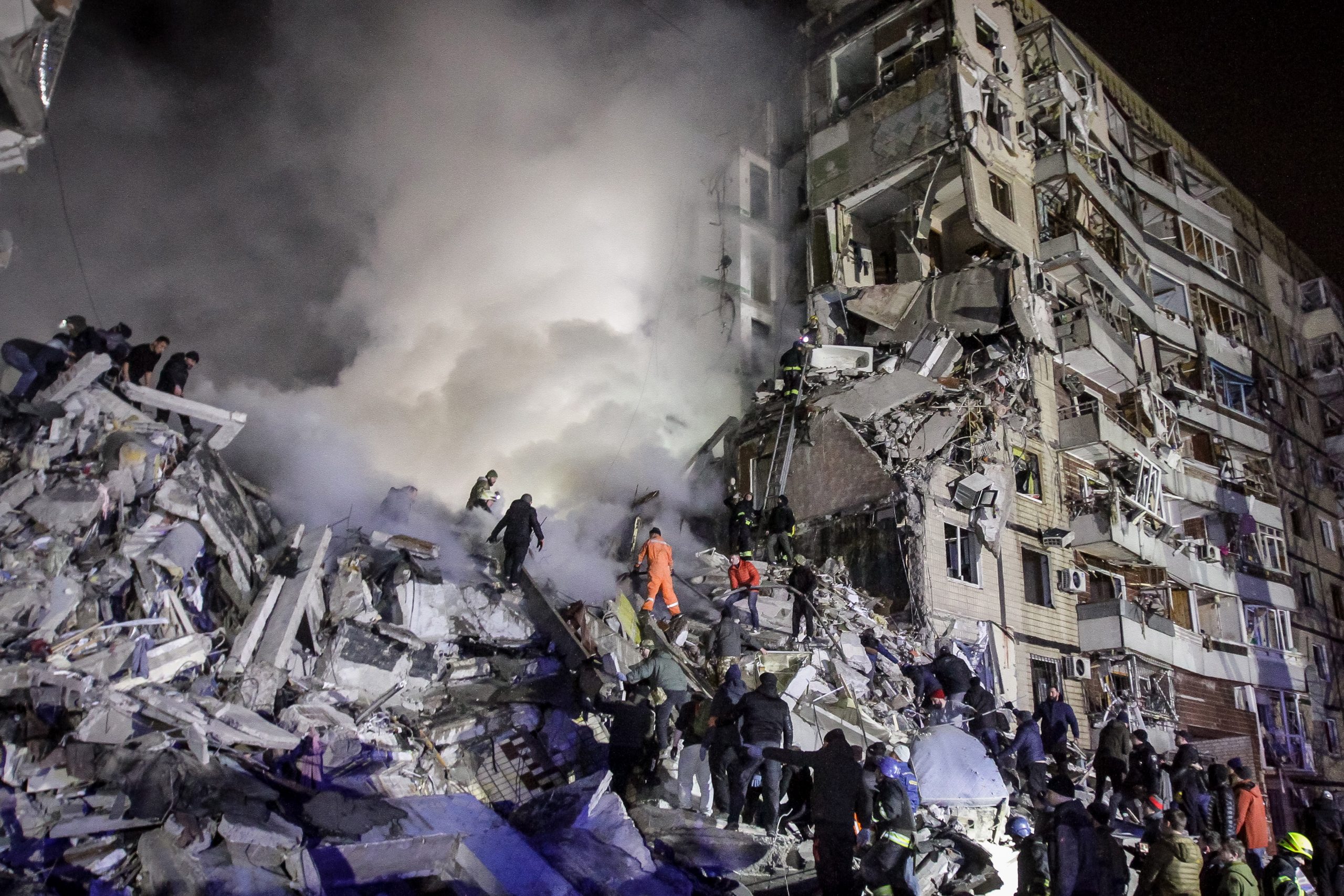 epa10405713 Local residents help with rescue operations at the site of a damaged residential building hit by shelling in Dnipro, southeastern Ukraine, 14 January 2023, amid Russia's invasion. At least five people died and 64 others were injured, including 14 children, after a rocket hit the nine-story building in Dnipro, the State Emergency Service (SES) of Ukraine reported on 14 January. Russian troops entered Ukraine on 24 February 2022 starting a conflict that has provoked destruction and a humanitarian crisis.  EPA/STR
