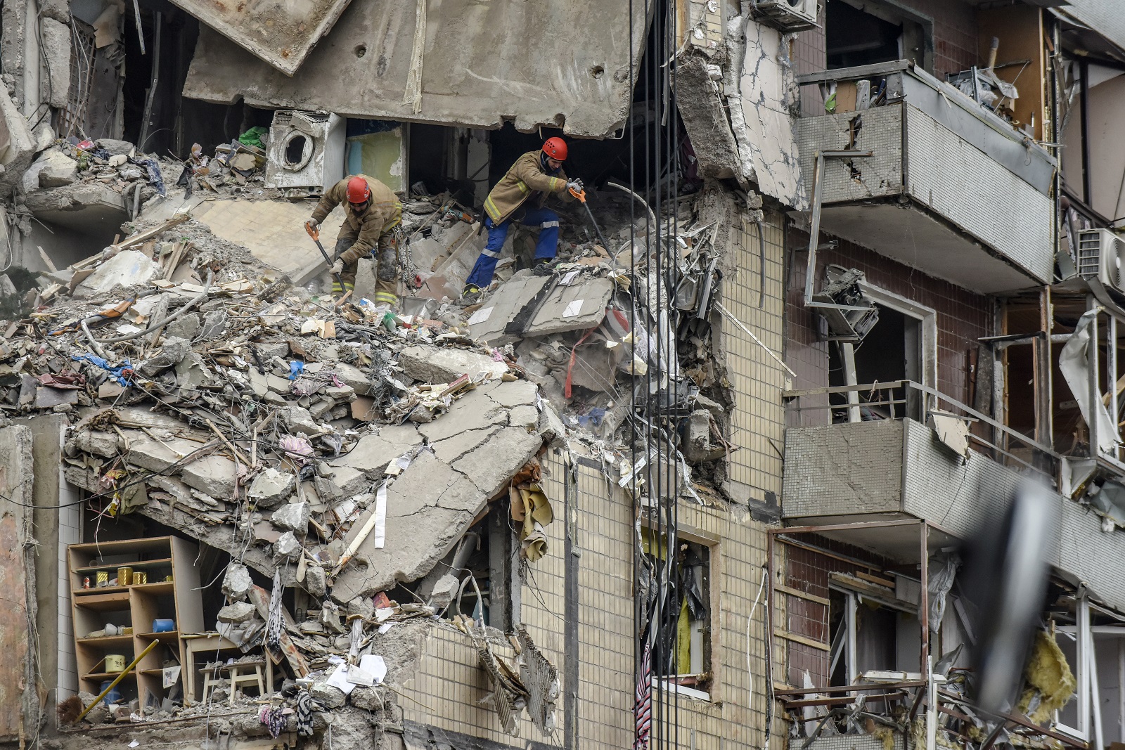 epa10407037 Rescue workers remove debris at the site of a damaged residential building in Dnipro, southeastern Ukraine, 15 January 2023, amid Russia's invasion. At least 25 people died, including one child, 73 other were injured, including 13 children, and 43 reports of missing persons were received, after a rocket hit a nine-story building in Dnipro on 14 January, the State Emergency Service (SES) of Ukraine said in a statement. Russian troops entered Ukraine on 24 February 2022 starting a conflict that has provoked destruction and a humanitarian crisis.  EPA/OLEG PERTASYUK
