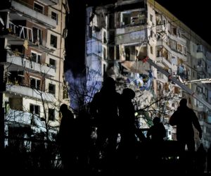epa10407418 A group of people stands near the site of a damaged residential building as rescue work continues, in Dnipro, southeastern Ukraine, 15 January 2023, amid Russia's invasion. At least 25 people died, including one child, 73 other were injured, including 13 children, and 43 reports of missing persons were received, after a rocket hit a nine-story building in Dnipro on 14 January, the State Emergency Service (SES) of Ukraine said in a statement. Russian troops entered Ukraine on 24 February 2022 starting a conflict that has provoked destruction and a humanitarian crisis.  EPA/OLEG PETRASYUK