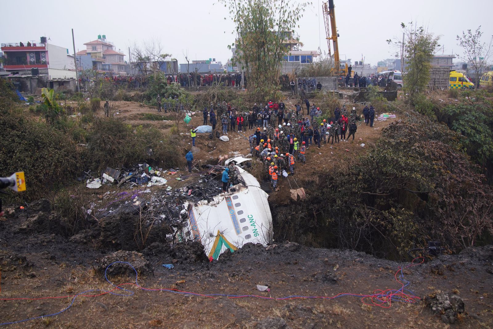 epa10408675 Rescue teams working near the wreckage at the crash site as they look for more bodies from a Yeti Airlines ATR72 aircraft in Pokhara, central Nepal, 16 January 2023. A Yeti Airlines ATR72 aircraft carrying 72 people on board, 68 passengers and 4 crew members, crashed into a gorge while trying to land at the Pokhara International Airport. According to a statement from the Civil Aviation Authority of Nepal (CAAN), at least 68 people were confirmed dead.  EPA/YUNISH GURUNG