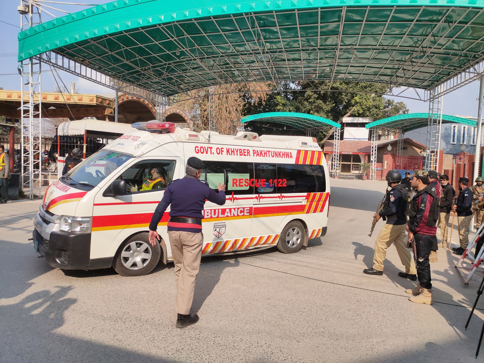 epa10439773 Pakistani security officials stand guard as an ambulance shift victims of a blast at a Mosque, in Peshawar, Pakistan, 30 January 2023. At least 19 worshippers were killed and dozens injured in a blast during prayers at a Mosque situated in Police lines in Peshawar, spokesman of the Lady Reading Hospital Peshawar said.  EPA/BILAWAL ARBAB