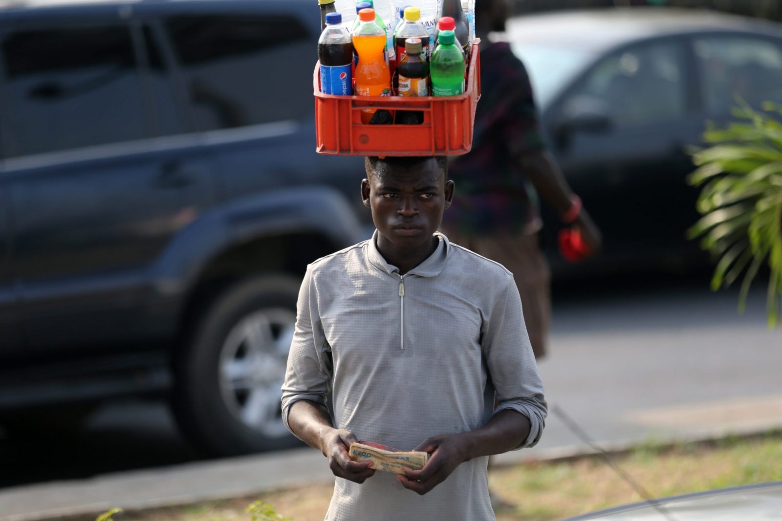 epa10446022 A man selling drinks in traffic holds the Nigeria naira currency notes along a road in Ikeja district of Lagos, Nigeria, 03 February 2023. The currency redesign policy by the Central Bank of Nigeria (CBN) aimed at checking counterfeiting and reducing the volume of money outside the banking system have come under public criticism, as the economy is cash crunched over the last week. The scarcity of the new redisgned currency have resulted in large crowds and long queues at cash points and banking halls in major cities across Nigeria.  EPA/Akintunde Akinleye
