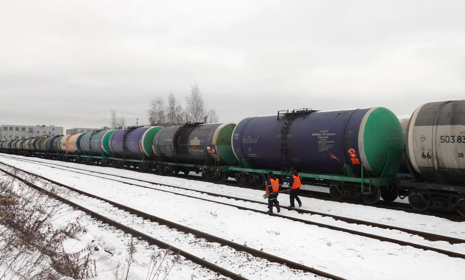 epa10450775 Workers walk in front of railway tankers carrying oil products outside Moscow, Russia, 06 February 2023. On 24 February 2022 Russian troops entered Ukrainian territory in what the Russian president declared a 'Special Military Operation', resulting in multiple sanctions against Russia, including sanctions against the oil industry.  EPA/MAXIM SHIPENKOV