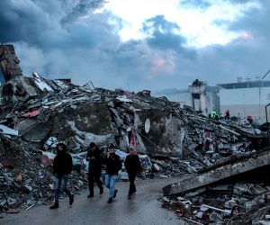 epa10452169 People walk at the site of a collapsed building following an earthquake in Iskenderun, district of Hatay, Turkey, 07 February 2023. More than 4,000 people were killed and thousands more injured after a major 7.8 magnitude earthquake struck southern Turkey and northern Syria on 06 February. Authorities fear the death toll will keep climbing as rescuers look for survivors across the region.  EPA/ERDEM SAHIN