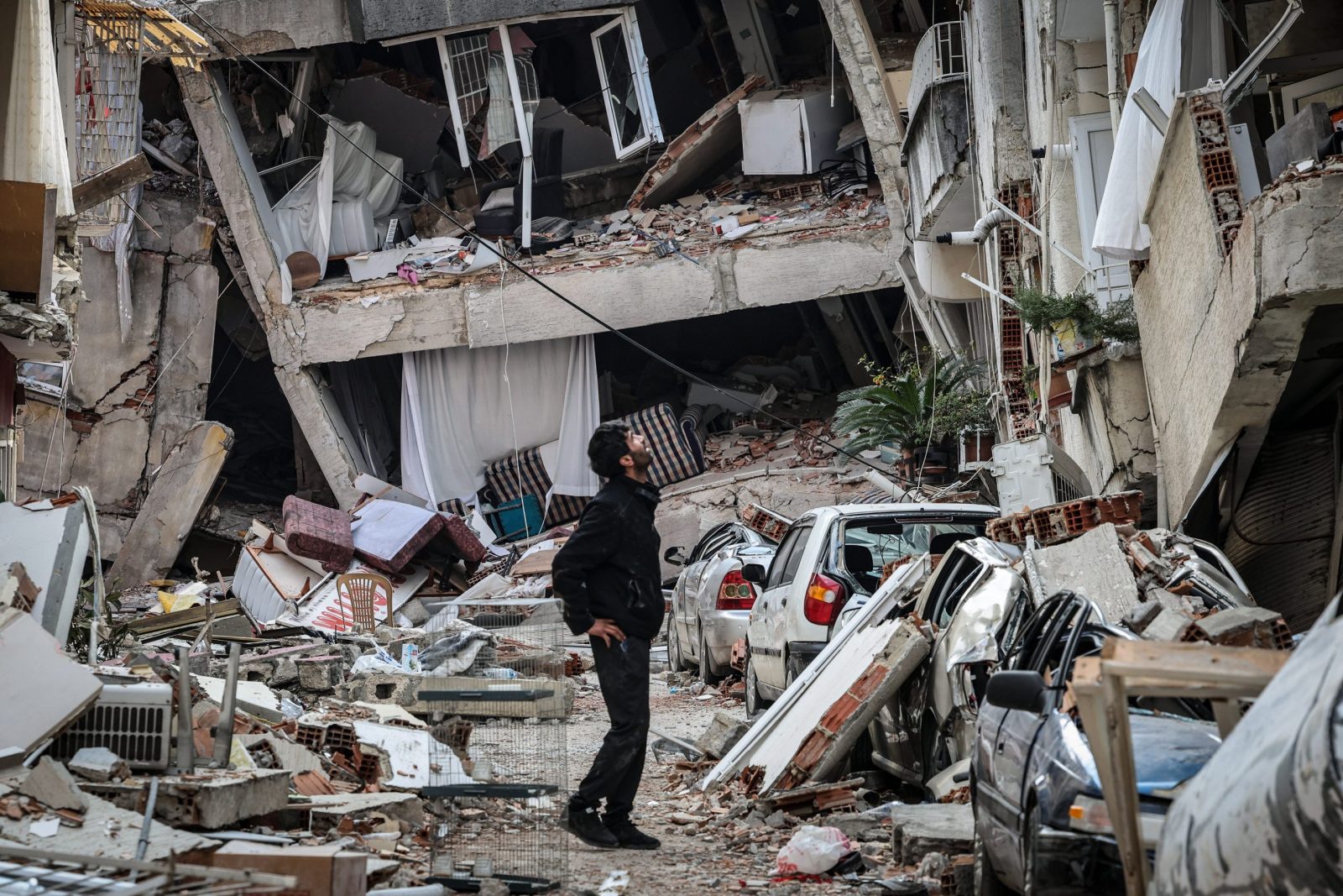 epa10460701 A survivor observes the damage of a collapsed building in Antakya capital of Hatay Province, the southernmost province of Turkey after the powerful earthquake, 11 February 2023. A team from Portugal of 53 Civil Protection, GNR, and emergency medical personnel left 08 February, for Turkey to support search and rescue efforts after 06 February earthquake, which has already killed more than 24,000 people in Turkey and Syria.  EPA/JOAO RELVAS