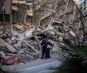 epa10470970 People walk past the site of collapsed buildings after a powerful earthquake, in Hatay, Turkey, 16 February 2023. More than 41,000 people have died and thousands more are injured after two major earthquakes struck southern Turkey and northern Syria on 06 February. Authorities fear the death toll will keep climbing as rescuers look for survivors across the region.  EPA/MARTIN DIVISEK