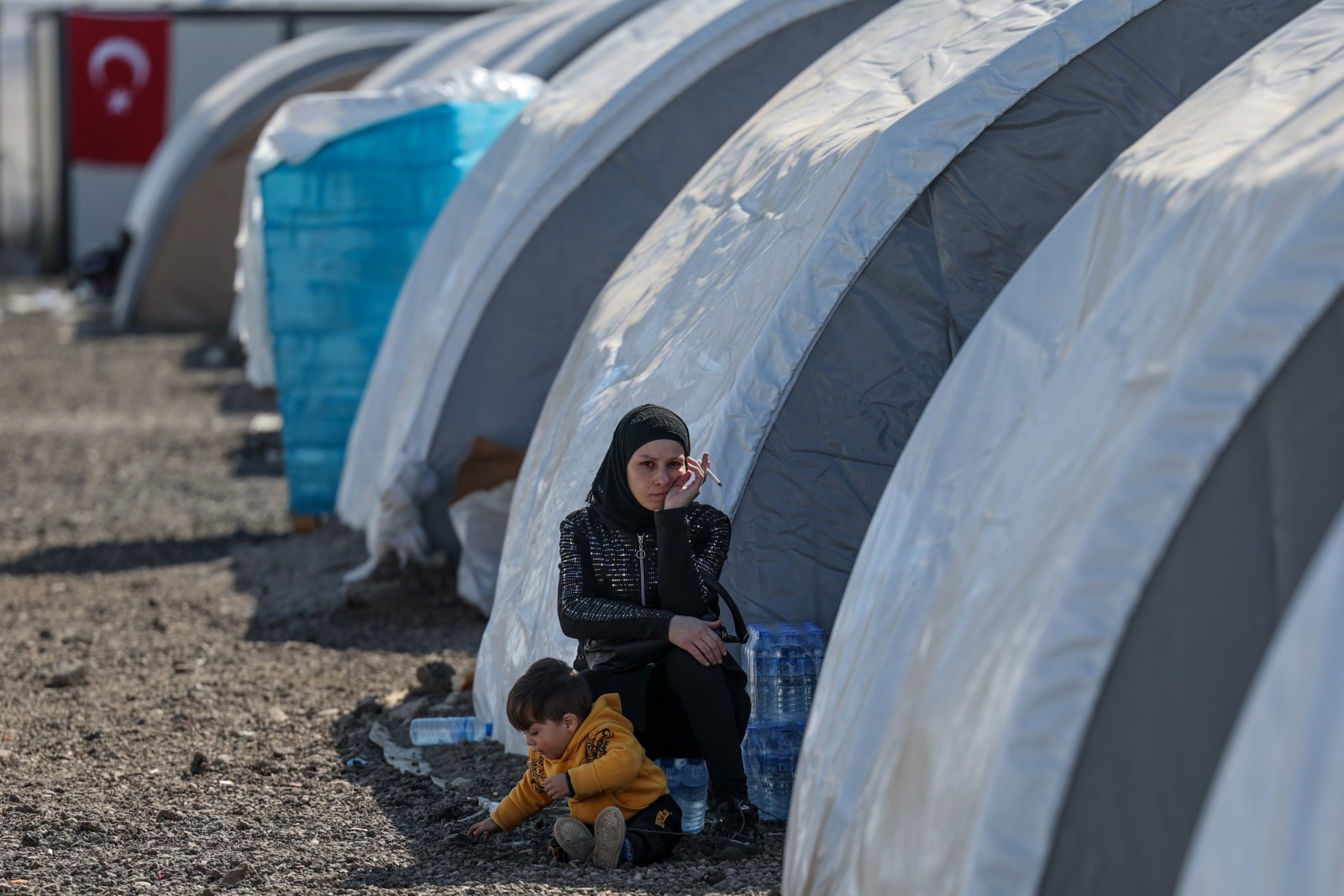 epa10475480 A woman affected by the earthquake sits next to her son inside a tent camp in Iskenderun district of Hatay, Turkey, 18 February 2023. More than 45,000 people have died and thousands more are injured after two major earthquakes struck southern Turkey and northern Syria on 06 February. Authorities fear the death toll will keep climbing as rescuers look for survivors across the region.  EPA/SEDAT SUNA