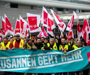 epa10472707 Workers hold union flags and a banner reading: 'Together goes more' at a demonstration outside of the international airport in Frankfurt am Main, Germany, 17 February 2023.  Following the strike announcement by the trade union ver.di, the operators of the airports in Frankfurt, Munich and Hamburg have announced that they will cease regular operations on Friday 17 February. All take-offs and landings of passenger flights and commercial connections are likely to be cancelled. According to the airport association ADV, the warning strike will lead to a good 2340 flight cancellations and could thus affect around 295.000 passengers.  EPA/HOSAM KATAN