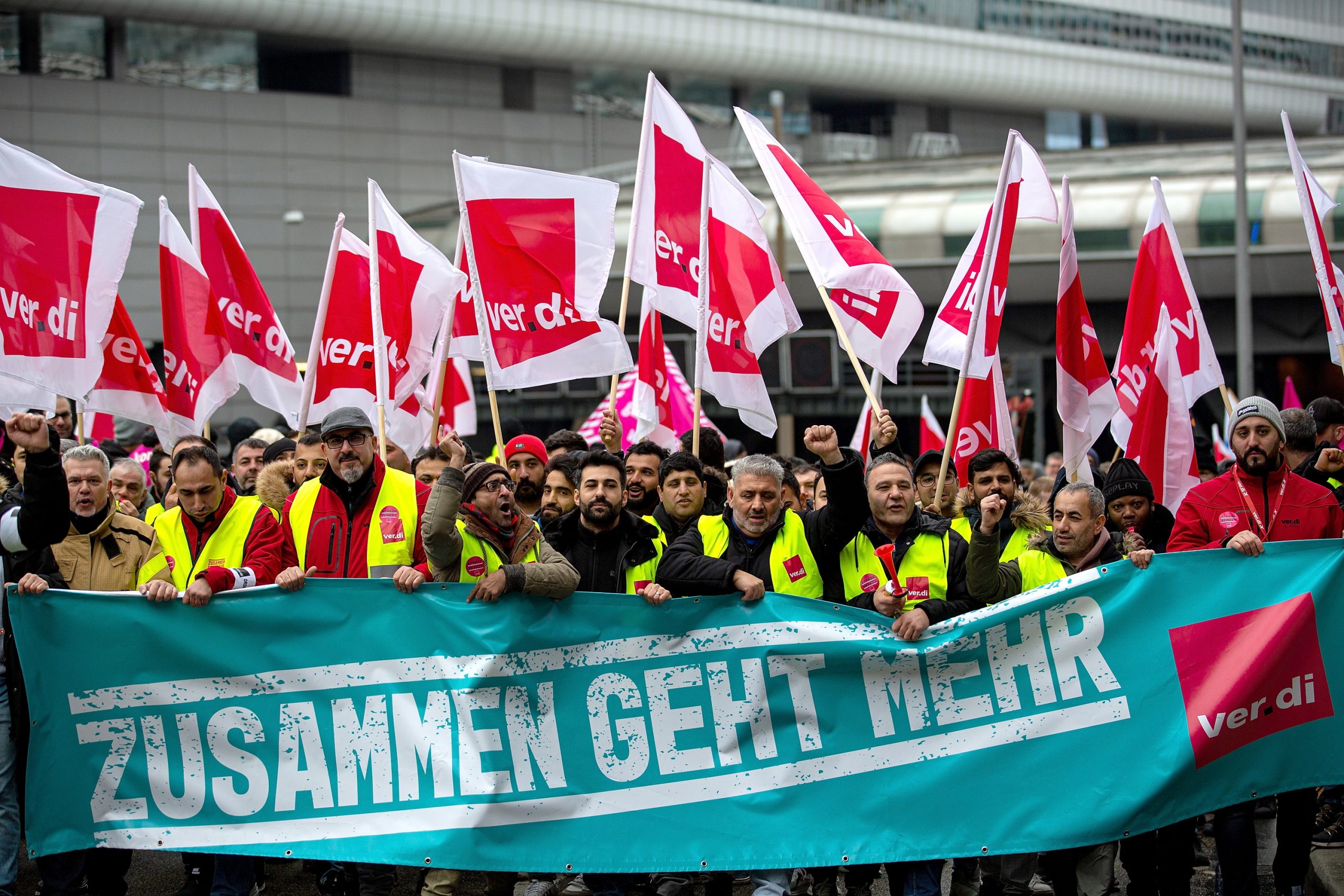 epa10472707 Workers hold union flags and a banner reading: 'Together goes more' at a demonstration outside of the international airport in Frankfurt am Main, Germany, 17 February 2023.  Following the strike announcement by the trade union ver.di, the operators of the airports in Frankfurt, Munich and Hamburg have announced that they will cease regular operations on Friday 17 February. All take-offs and landings of passenger flights and commercial connections are likely to be cancelled. According to the airport association ADV, the warning strike will lead to a good 2340 flight cancellations and could thus affect around 295.000 passengers.  EPA/HOSAM KATAN